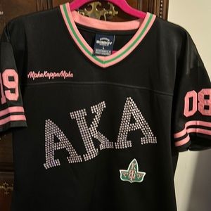 Poly V-neck shirt! Sparkly AKA written on front, patch on back. 1908 on sleeves!